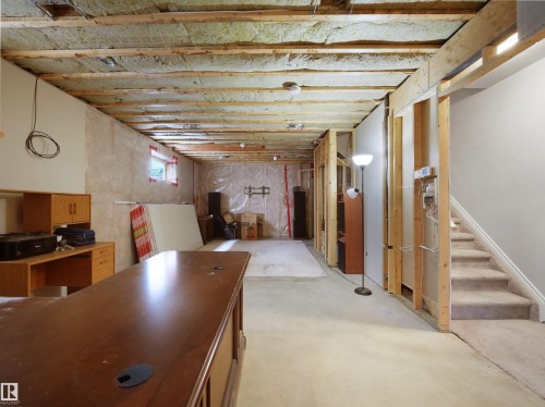 Unfinished basement space featuring exposed ceiling joists with insulation, framed walls, and a carpeted staircase - 45 Willow Wood Lane, Stony Plain, AB 