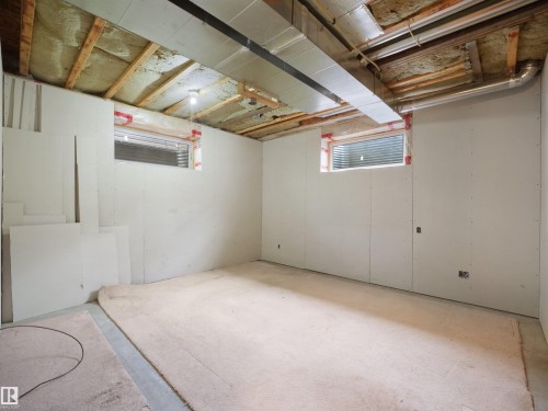 Room with unfinished drywall walls, exposed ceiling joists, and two rectangular windows - 45 Willow Wood Lane, Stony Plain, AB 