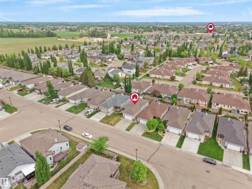Aerial perspective showcasing a residential area with single-family homes, green lawns, and mature trees - 45 Willow Wood Lane, Stony Plain, AB 