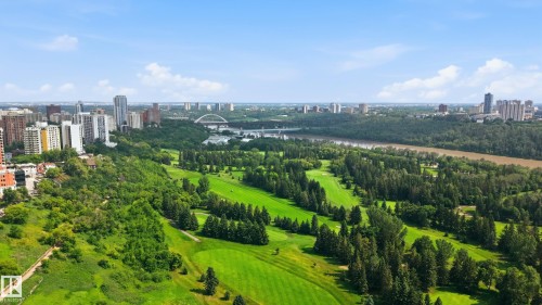 Expansive golf course greens surrounded by mature trees, with a river and urban skyline in the background - 504 11710 100 Avenue, Edmonton, AB 
