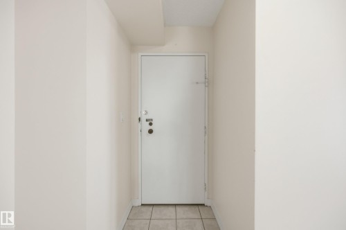 White entry door with multiple security locks, light beige wall paint, and square tile flooring - 504 11710 100 Avenue, Edmonton, AB 