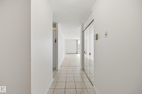 Entryway with square tile flooring, mirrored sliding closet doors, and smooth white walls - 504 11710 100 Avenue, Edmonton, AB 