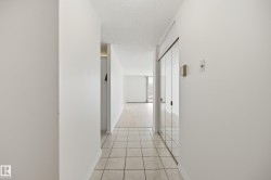 Entryway with square tile flooring, mirrored sliding closet doors, and smooth white walls - 