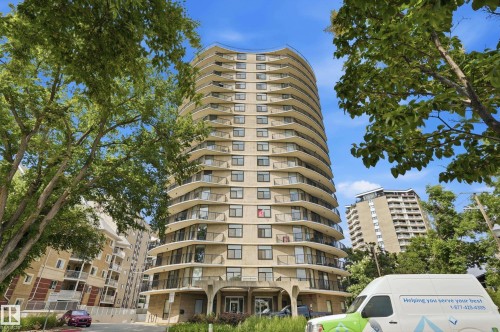 High-rise building featuring a curved architectural design, multiple private balconies with railings, a stone exterior finish, and ground-level landscaping - 504 11710 100 Avenue, Edmonton, AB 