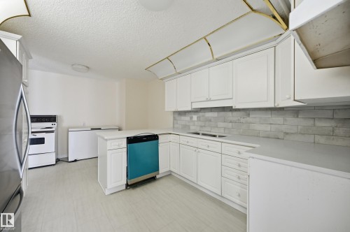 Kitchen featuring white cabinetry, light-toned countertops, and a gray subway tile backsplash - 504 11710 100 Avenue, Edmonton, AB 