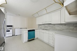 Kitchen featuring white cabinetry, light-toned countertops, and a gray subway tile backsplash - 