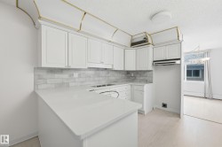 Modern kitchen featuring white shaker cabinetry, light-colored countertops, and a white subway tile backsplash - 