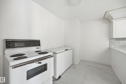 Kitchenette featuring an electric range, white cabinetry, a light-toned countertop, and a subway tile backsplash - 