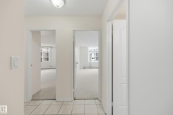 Tiled entryway flooring extends into the hallway with neutral wall tones and flush-mount lighting - 