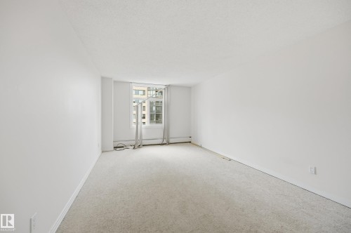 Bright room featuring light-toned carpet flooring, white walls, and a window with white trim - 504 11710 100 Avenue, Edmonton, AB 