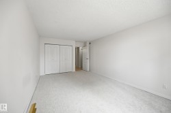 White walls complement the light-toned carpeting in this room featuring bi-fold closet doors and a textured ceiling - 