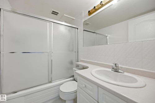 Bathroom featuring a white vanity with an integrated sink, chrome faucet, and a large mirror - 504 11710 100 Avenue, Edmonton, AB 