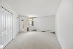 Spacious interior room featuring light-colored carpet flooring, white walls, and a large window - 