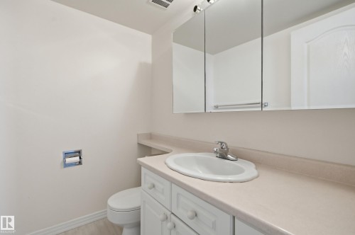 Bathroom featuring a single vanity with an integrated sink, light-toned countertop, and white cabinetry - 504 11710 100 Avenue, Edmonton, AB 