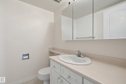Bathroom featuring a single vanity with an integrated sink, light-toned countertop, and white cabinetry - 