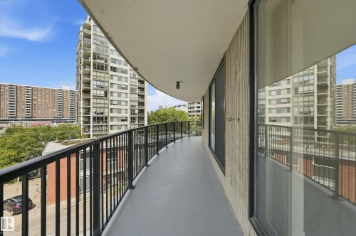 Curved balcony featuring a dark gray concrete floor, black metal railing, and textured exterior wall - 504 11710 100 Avenue, Edmonton, AB 