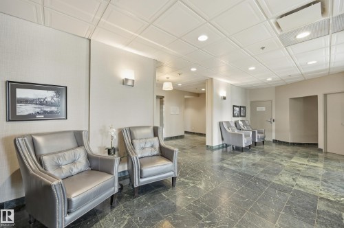 Expansive common area featuring green marble-finish flooring, textured wall coverings, and recessed ceiling lighting - 504 11710 100 Avenue, Edmonton, AB 