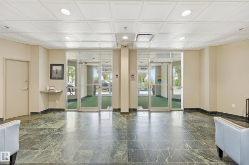 Lobby area featuring large format green marble-look tile flooring and a contrasting dark baseboard - 504 11710 100 Avenue, Edmonton, AB 