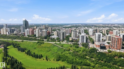 Expansive cityscape featuring a collection of high-rise buildings, extensive green spaces, a meandering road, and a golf course with manicured fairways - 504 11710 100 Avenue, Edmonton, AB 