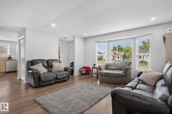 Living area featuring wood-finish flooring, recessed lighting, a bay window with horizontal blinds, and light-toned walls - 