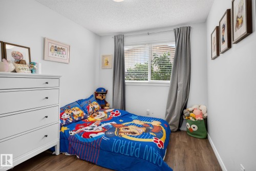 Bedroom featuring wood-finish flooring, a double window with blinds, and light-toned walls - 3218 41 Street, Leduc, AB 