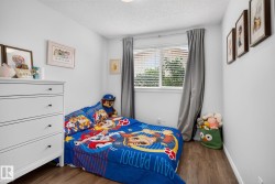 Bedroom featuring wood-finish flooring, a double window with blinds, and light-toned walls - 