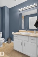 Bathroom featuring a white vanity with brushed nickel hardware, an integrated sink, and a light-toned countertop - 