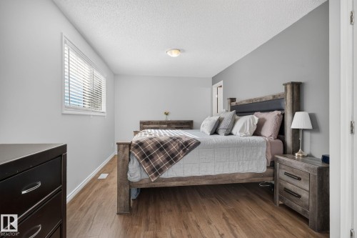 Bedroom featuring wood-finish flooring, light gray wall paint, and white trim - 3218 41 Street, Leduc, AB 