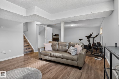 Finished lower level featuring wood-finish flooring, light gray wall paint, white trim, and a carpeted staircase - 3218 41 Street, Leduc, AB 