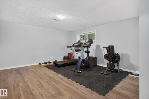 Spacious room featuring wood-finish flooring, light gray walls, white trim, and a white ceiling - 3218 41 Street, Leduc, AB 