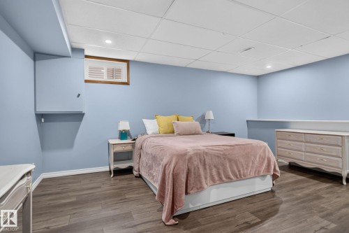 Spacious room featuring wood-finish flooring, light blue walls, and a white grid ceiling with recessed lighting - 3218 41 Street, Leduc, AB 