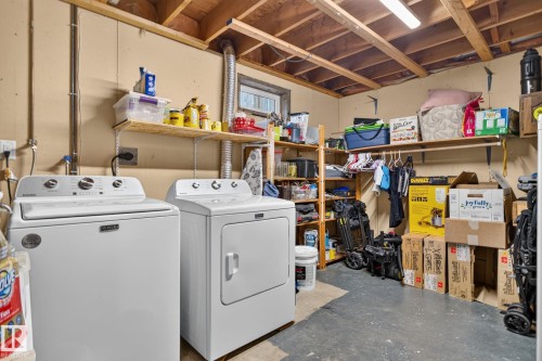 Dedicated laundry area featuring a washer and dryer, exposed ceiling joists, and a concrete floor - 3218 41 Street, Leduc, AB 