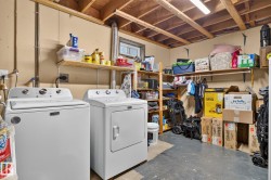 Dedicated laundry area featuring a washer and dryer, exposed ceiling joists, and a concrete floor - 