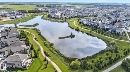Expansive residential community with a central lake featuring a walking path, mature landscaping, and numerous properties with private decks - 3218 41 Street, Leduc, AB 