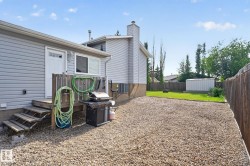 Backyard featuring a gravel patio area, wooden deck with stairs, a white exterior door, and a white storage shed - 
