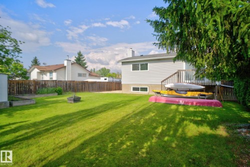 Expansive green lawn with a wood privacy fence and established trees - 3218 41 Street, Leduc, AB 