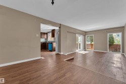 Open-concept living space with wood-finish flooring, neutral paint, and two sets of sliding glass doors - 