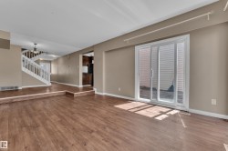 Spacious living area featuring wood-finish flooring, a sliding glass door for outdoor access, and neutral wall tones - 