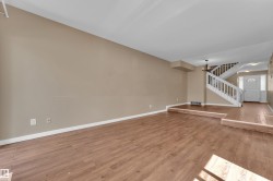 Spacious living area featuring wood-finish flooring, neutral wall tones, and white trim - 