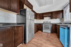 Kitchen featuring wood-finish flooring, dark wood cabinetry, solid surface countertops, and a tile backsplash - 