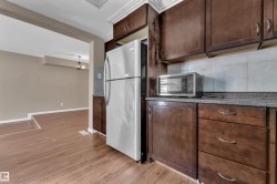 Kitchen featuring wood-finish flooring, dark wood cabinetry, and a light-colored tile backsplash - 