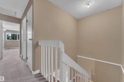 Stairwell featuring a white wooden railing and beige painted walls - 