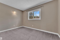 Neutral tone walls with white trim, a single casement window, and wall-mounted light fixture - 