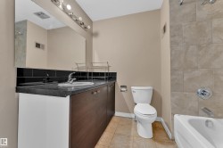 Bathroom with a dark countertop vanity featuring an integrated sink and chrome faucet - 