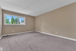 Spacious room featuring neutral-toned walls, gray carpeting, and white baseboards - 
