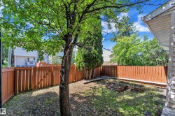 Private backyard space featuring a mature tree, perimeter wood fencing, and raised garden beds - 