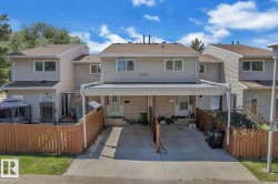 Multi-unit residential property featuring carports, private fenced outdoor areas, and light-colored siding - 