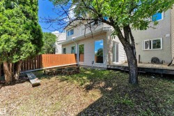 Fenced backyard featuring mature trees, a wooden deck, and a sliding glass door for outdoor access - 