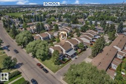 Aerial perspective of a multi-unit property within a residential development, featuring a brown shingle roof, private fenced yards, and mature perimeter trees - 