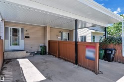 Covered carport with concrete flooring, supported by dark posts, featuring a white aluminum soffit - 